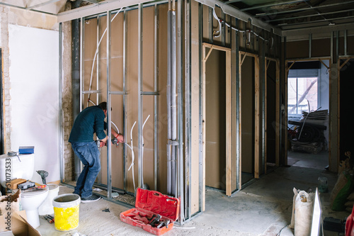 Man installing wall piping in new apartment