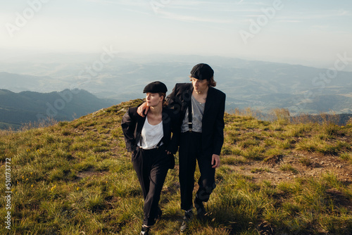 Stylish couple in black suits on a walk among mountain landscapes