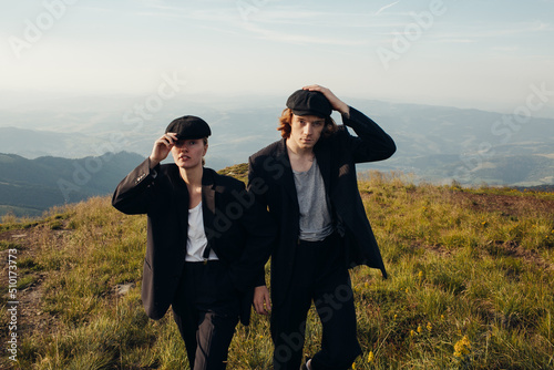 Beautiful couple in black suits and caps in the mountains photo