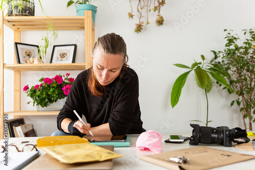 Woman using ipad and stylus at a desk photo