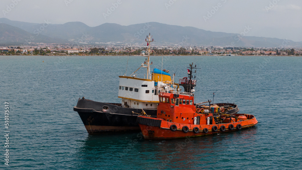 two colourful tugboats moored together in the sea two colourful tugboats moored together in the sea
