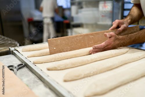 Crop man making baguettes from dough
