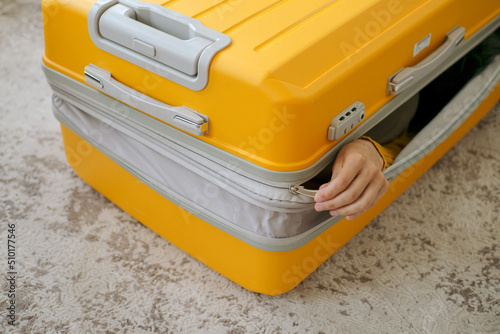 An unrecognizable person packed into a travel suitcase