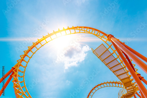 Fototapeta Naklejka Na Ścianę i Meble -  Rollercoaster railroad  track high to the sky roll bend and twist exciting machine fun people at theme park.