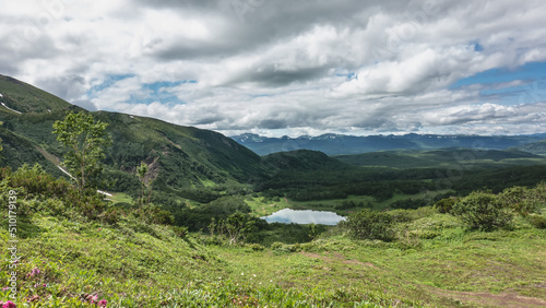 View of the lake from the mountain slope. The meadow has lush green vegetation. The path goes down. Picturesque clouds in the blue sky. Reflection. Kamchatka. Vachkazhets. Lake Tahkoloch © Вера 
