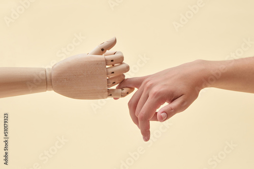Two little fingers of doll and woman are together.