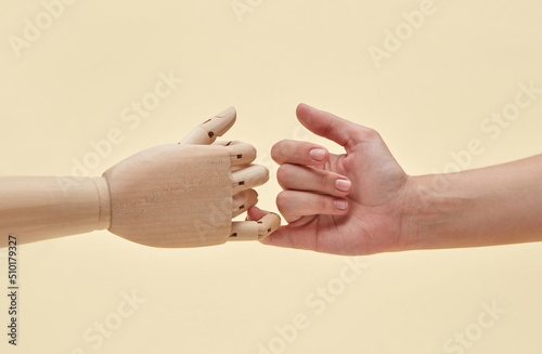 Two little fingers of mannequin and woman are together. photo
