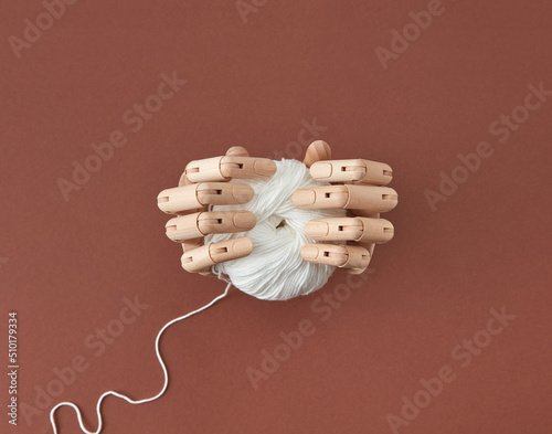 Artificial mannequin's hands hold the ball of thread.