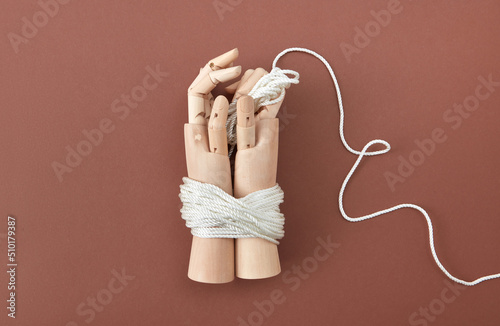 Wooden dummy's hands tied with rope.