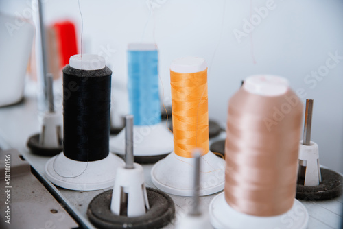 Close-up spool of multicolored threads for sewing machine. Concept Interior of garment factory