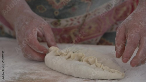 Traditional Armenian food - Zhengyal bread. Baker's hand making traditional dish in Eastern Asia.  Baker's hand making  Armenian food - Zhengyal bread. Sliced herbs in dough. photo