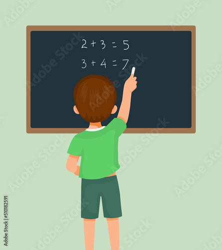 Back view of cute little boy student write on blackboard math equation in front of class with chalk