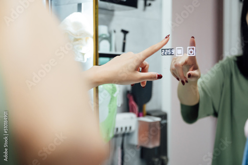 Young woman using electronically mirror at home photo