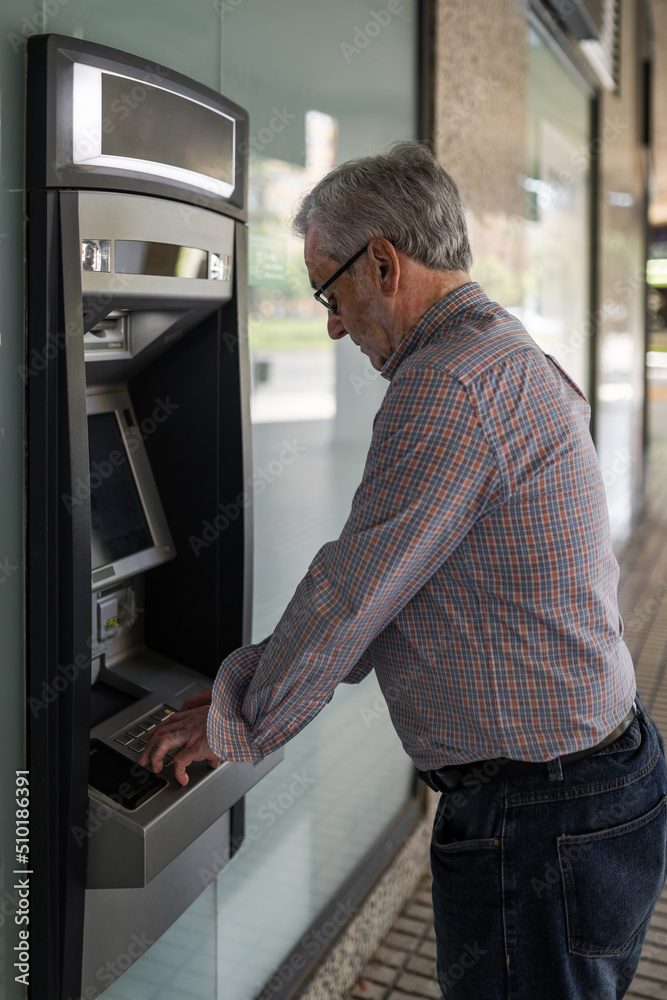 senior man at an ATM withdrawing cash senior man at an ATM withdrawing cash