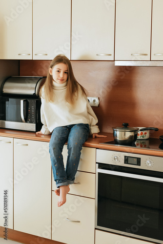 girl 9 years old with long hair model plays with pet white dog maltese school girl at home lifestyle in beige kitchen no allergy veterinarian