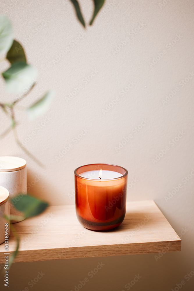 Aromatic candle on shelf in sunlit room