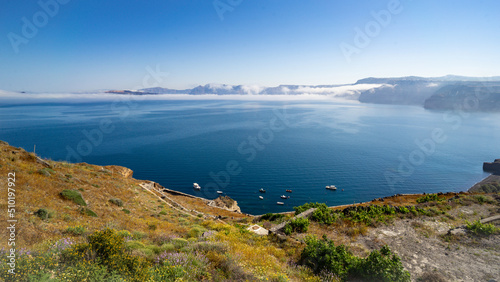 A panoramic view of Santorini's caldera from south to north with a small fishing harbour in the foreground 