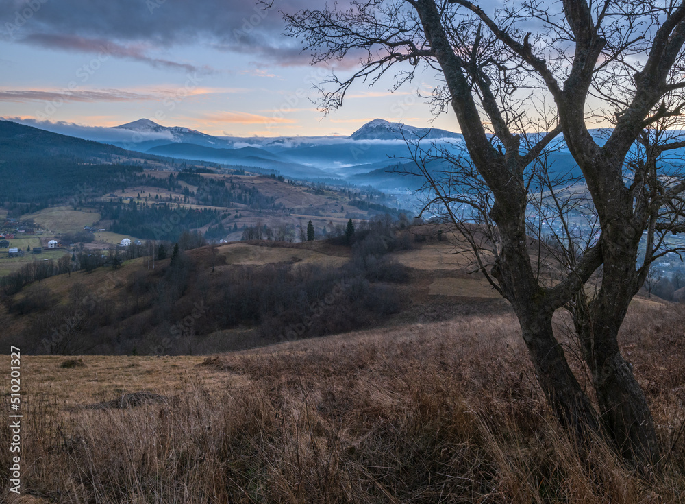 Picturesque pre sunrise morning above late autumn mountain countryside. Ukraine, Carpathian Mountains, Hoverla and Petros tops in far. Picturesque pre sunrise morning above late autumn mountain countryside. Ukraine, Carpathian Mountains, Hoverla and Petros tops in far.