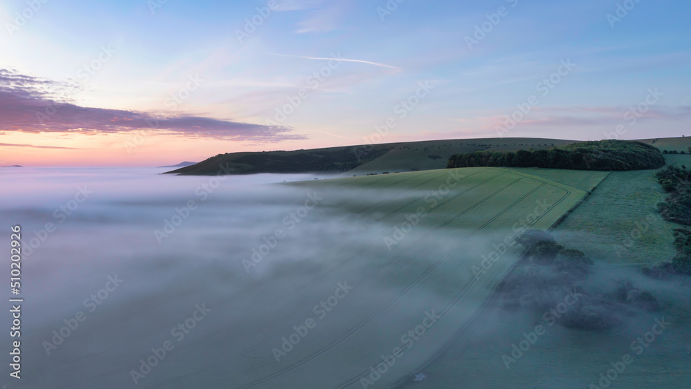 Majestic drone landscape image of sea of fog rolling across South Downs English countryside during Spring sunrise Majestic drone landscape image of sea of fog rolling across South Downs English countryside during Spring sunrise