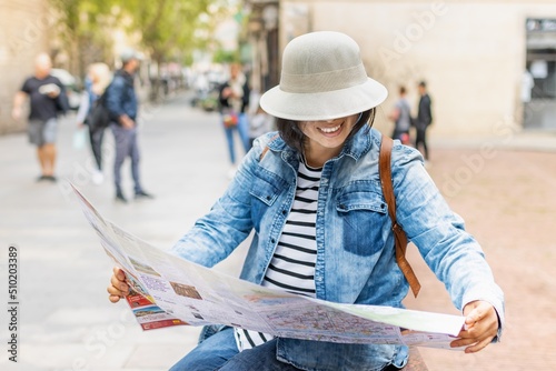 Smiling Latina tourist consulting the map in the Gothic Quarter of Barcelona  Spain   travel concept.