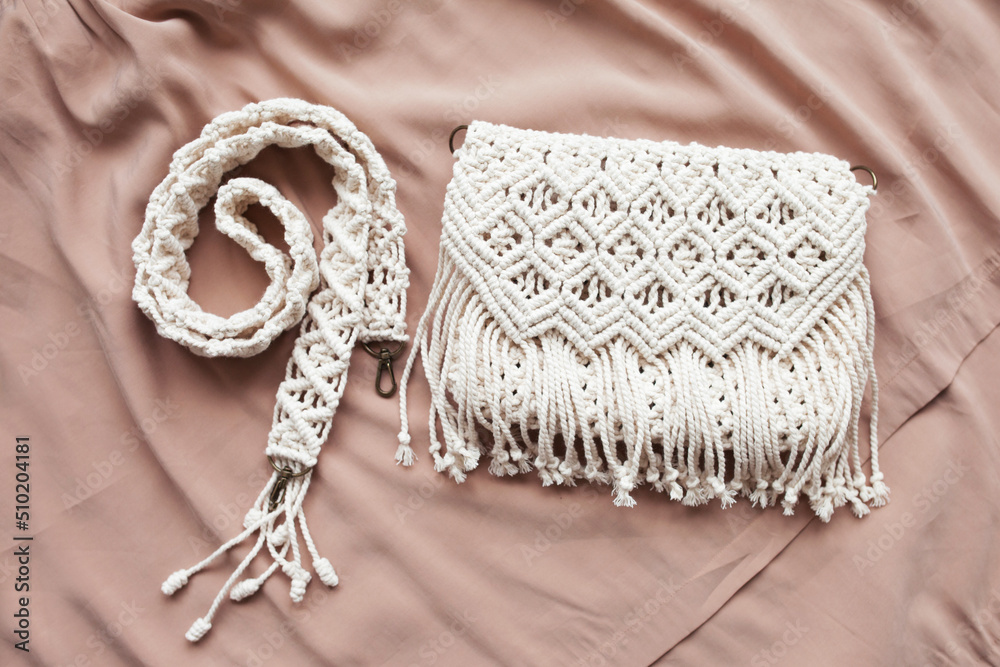 Fototapeta premium Handmade macrame cotton сross-body bag. Eco bag for women from cotton rope. Scandinavian style bag. Creme tones, sustainable fashion accessories. Close up image