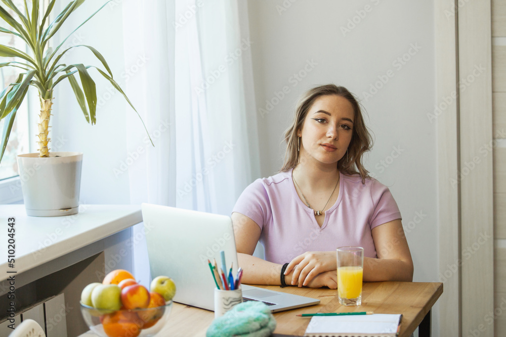 the girls are sitting at the table, eating fruit, drinking juice. They study on a laptop and look at the phone