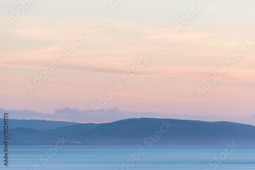 Stunning landscape image of pastel color sunset over ocean giving lovely soft dreamy relaxing feel