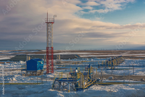 Wells producing natural gas at a field in the Arctic. Fountain equipment and technological strapping of a group of wells for gas production. Winter. Day. Gas production company infrastructure