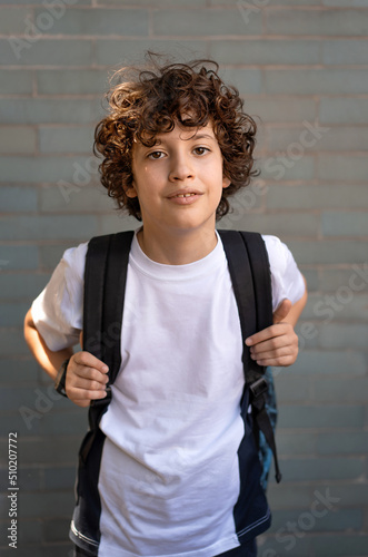 Portrait of a 10 year old schoolboy with backpack on the background of the school wall - concept of back to school for the beginning of the school year photo