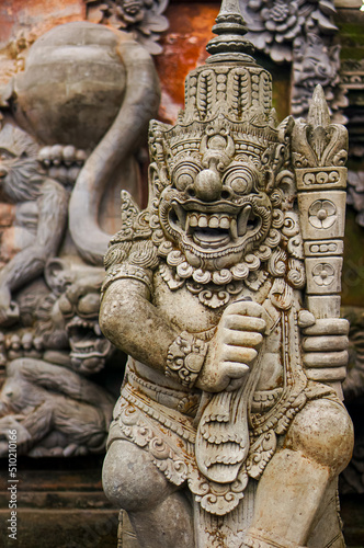 Selective focus stone statue in Temple Batu Bolong near, Tanah Lot, Bali, Indonesia. Carved statue with fine details that stands outside the entrance to Hindu temple as a guardian. Balinese culture.