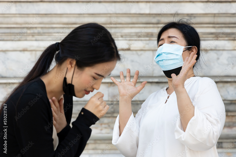 Young woman starts removing face mask and cough but senior woman still does not taking off face mask Young woman starts removing face mask and cough but senior woman still does not taking off face mask