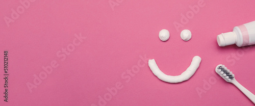 Smiling face made of toothpaste, brush and tube on pink background, flat lay with space for text. Banner design