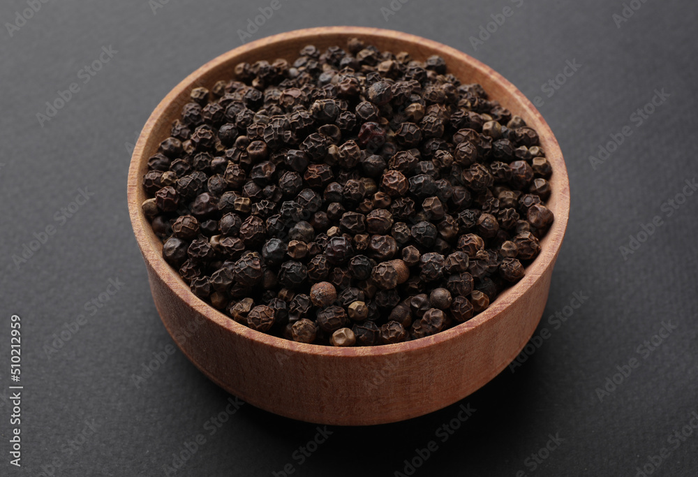 Wooden bowl of black peppercorns on dark background Wooden bowl of black peppercorns on dark background