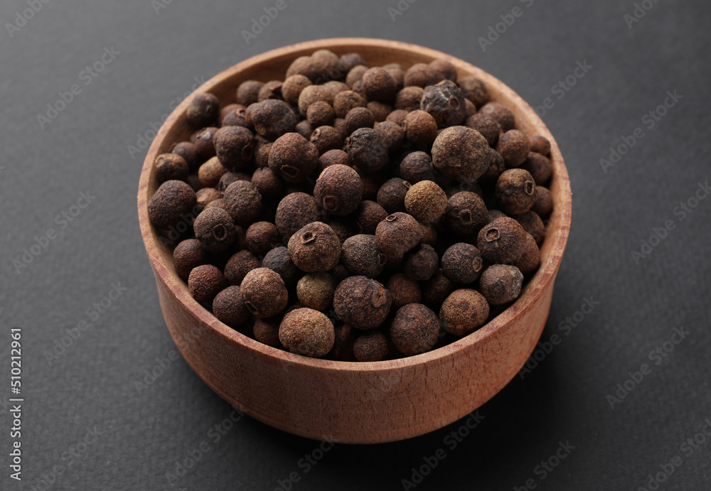 Wooden bowl of allspice grains on dark background Wooden bowl of allspice grains on dark background