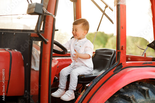 Sweet little boy sitting in a tractor at sunset