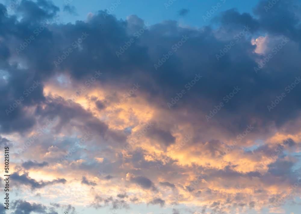Dramatic cumulus clouds on sunny day at golden hour painted with sun. Atmosphere background or wallpaper
