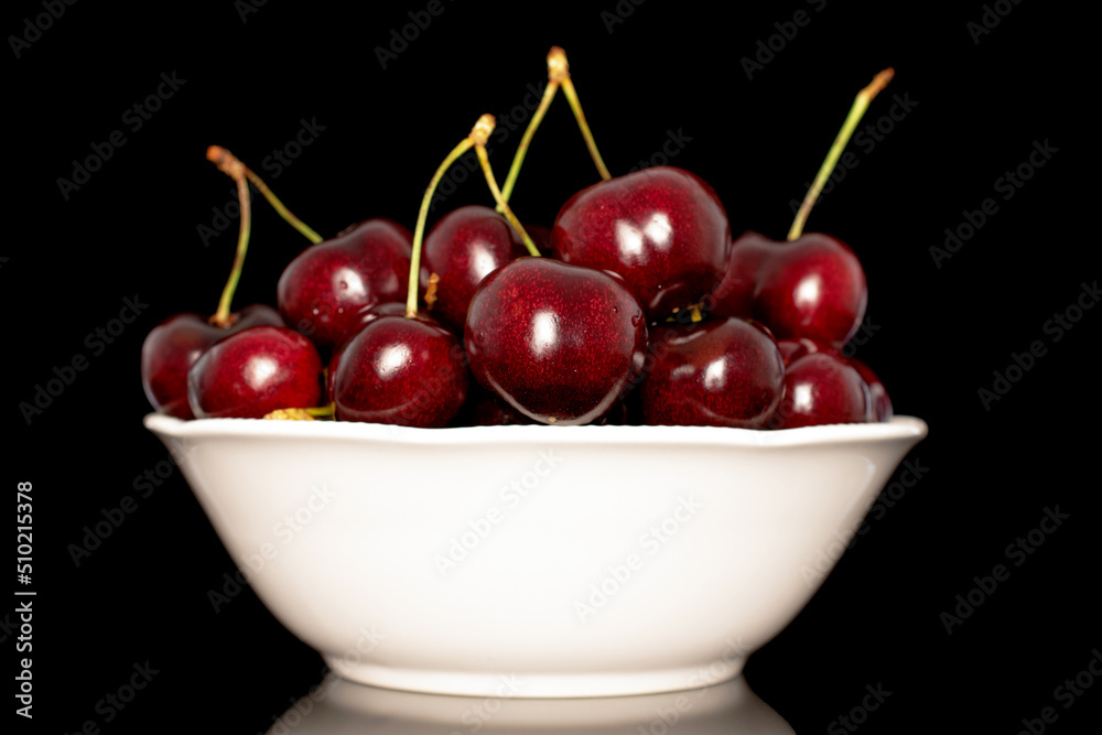Several sweet cherries with a white ceramic saucer, close-up, isolated on a black background. Several sweet cherries with a white ceramic saucer, close-up, isolated on a black background.