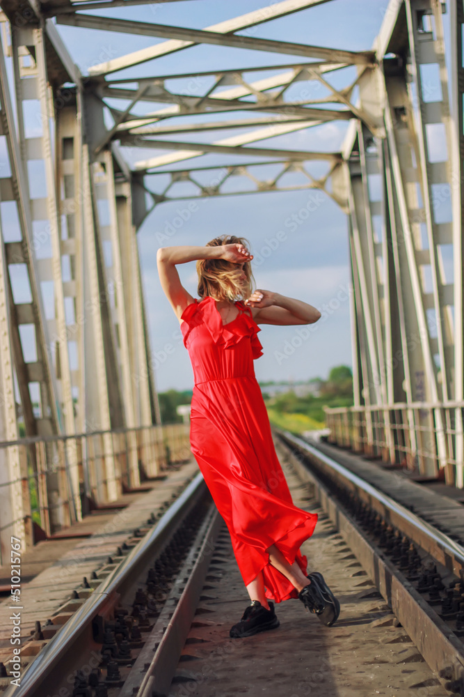 Girl in a red dress on the railroad	