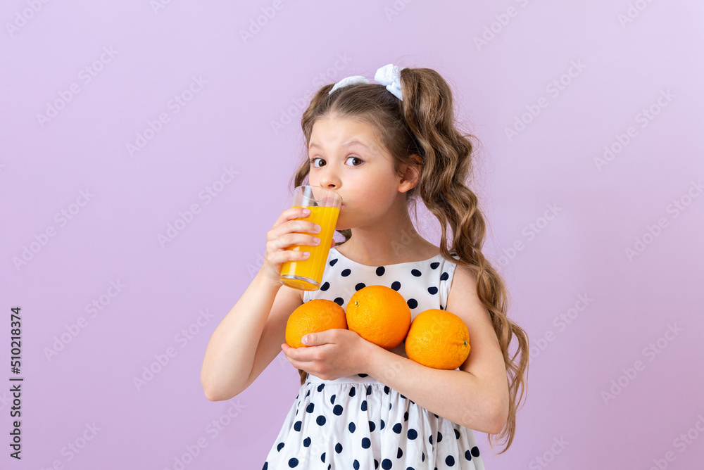 The child drinks orange juice. Freshly squeezed juice for baby food. Isolated background. The child drinks orange juice. Freshly squeezed juice for baby food. Isolated background.