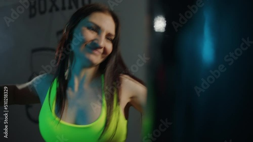 A sporty woman in a tracksuit hits a punching bag in the gym during a workout photo