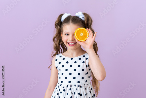 The child covered one eye with an orange. Citrus fruits for children s nutrition.