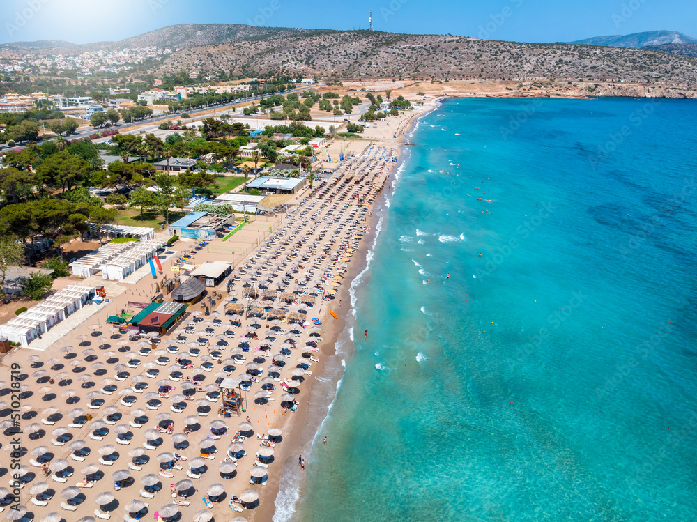 Aerial view of the beach resort at Varkiza, south Athens coast, Attica, Greece, with lined up umbrellas next to the turquoise sea