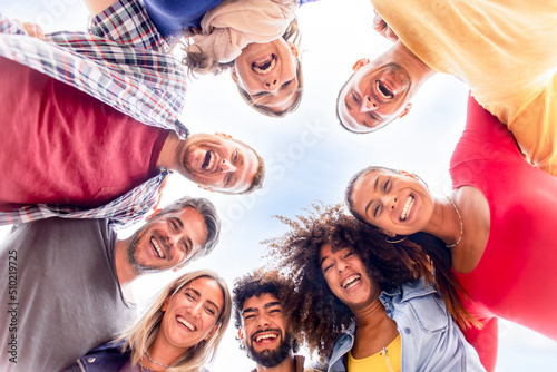 directly below portrait of interracial group of friends posing in the street outdoors laughing and having fun. diverse people celebrating life together enjoying happy holidays. lifestyle concept