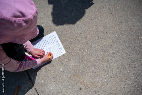 Fényképezés Young girl completing a zoo scavenger hunt form outdoors in the spring