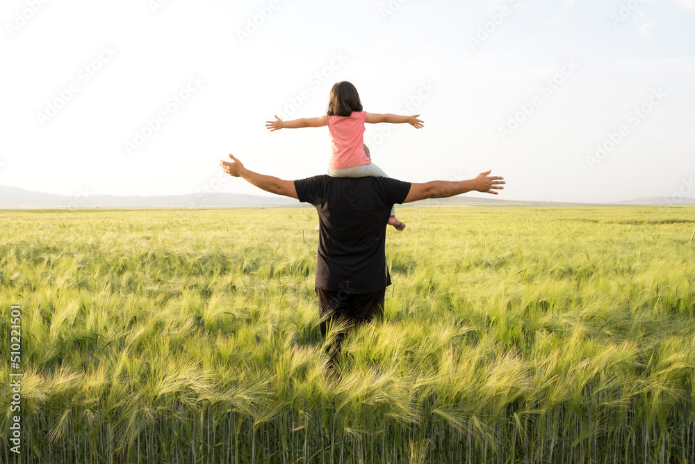Farmer father, daughter plays on shoulders of farmer father. Happy child and father playing in the wheat field. Father's Day concept idea photo with copy space. Farmer father, daughter plays on shoulders of farmer father. Happy child and father playing in the wheat field. Father's Day concept idea photo with copy space.