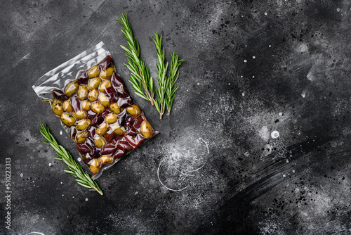 Greece olives in plastic pack, on black dark stone table background, top view flat lay, with copy space for text