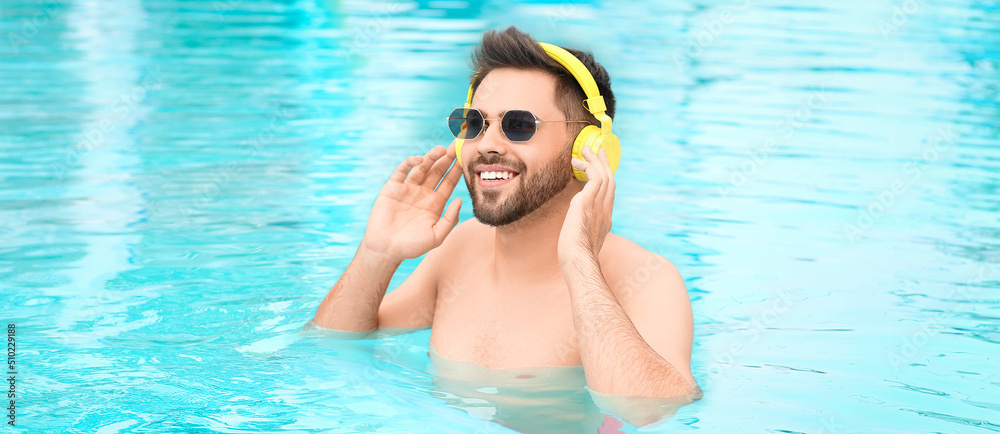 Happy young man listening to music in swimming pool