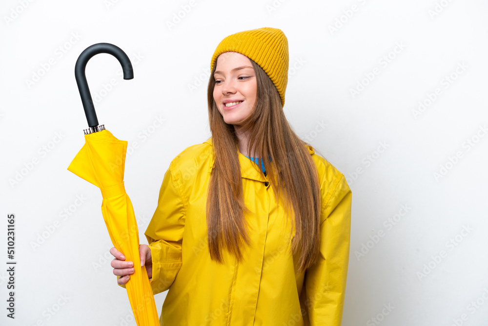 Young caucasian woman with rainproof coat and umbrella isolated on white background looking to the side and smiling Young caucasian woman with rainproof coat and umbrella isolated on white background looking to the side and smiling