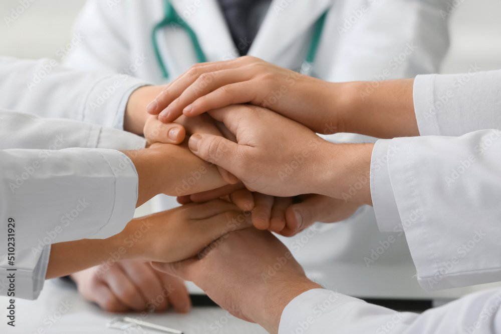Group of doctors putting hands together in clinic, closeup