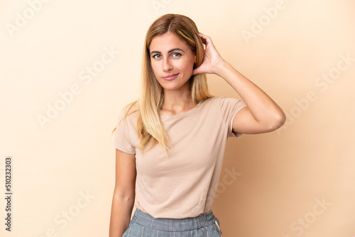 Blonde Uruguayan girl isolated on beige background having doubts